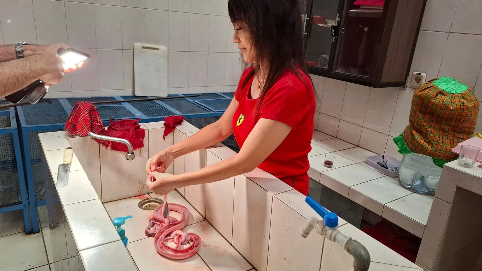 Titik membersihkan ular kobra yang baru disembelih. Foto: Aisyah Nawangsari Putri