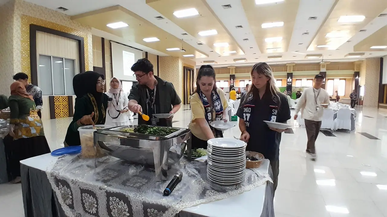 Mahasiswa asing peserta WAEJUC 2024 mencicipi kuliner khas Indonesia, Nasi Pecel di UIN Malang/Foto: Tugumalang.id/Bagus Rachmad Saputra.