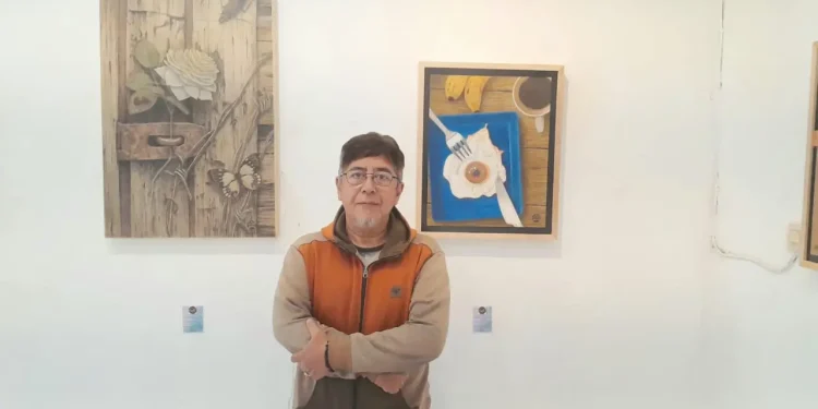 Salah satu pegiat seni Komunitas Tandur, Teguh Nuswantoro berpose bersama karya seni miliknya yang dipamerkan di pameran seni Bhinneka Tunggal Rasa./Foto: Tugumalang.id/Bagus Rachmad Saputra.