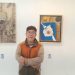 Salah satu pegiat seni Komunitas Tandur, Teguh Nuswantoro berpose bersama karya seni miliknya yang dipamerkan di pameran seni Bhinneka Tunggal Rasa./Foto: Tugumalang.id/Bagus Rachmad Saputra.