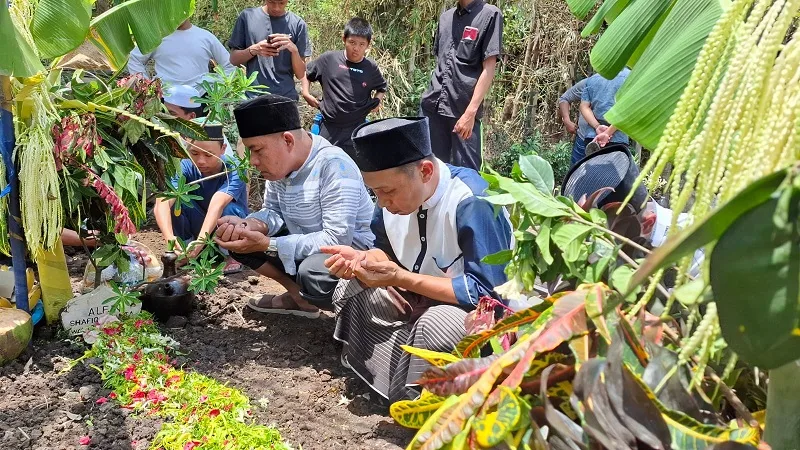 Kerabat membacakan doa di makam korban. Foto: Aisyah Nawangsari Putri