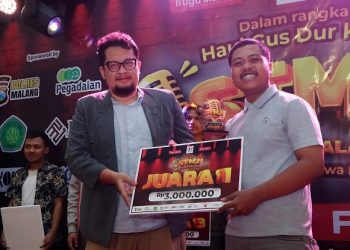Komika asal Malang, Bagus Sadewa menerima trofi dan hadiah Juara 1 STMJ 2025 yang diberikan oleh CEO Tugu Media Group, Irham Thoriq. /Foto: Tugumalang.id/Rubianto.