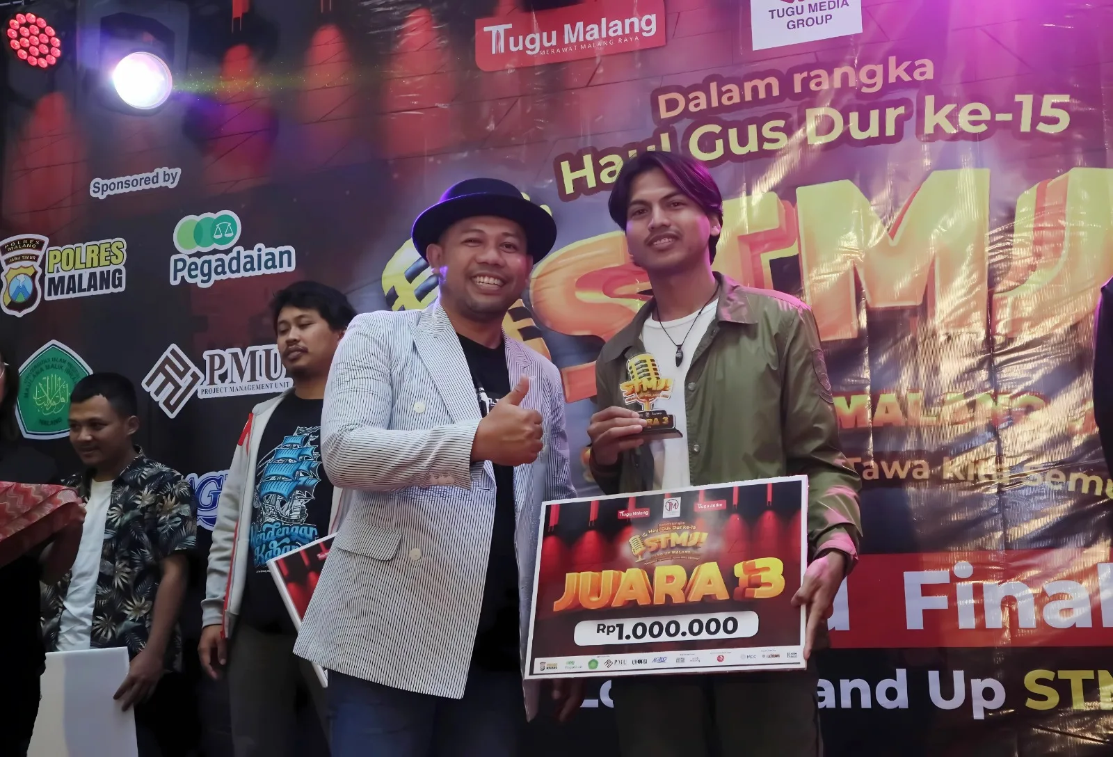 Komika asal Padang yang berkuliah di UIN Malang, Hidayat Putra menerima trofi Juara 3 STMJ 2025 yang diberikan Kepala Humas Unikama, Fahmi Arif Zakaria./Foto: Tugumalang.id/Rubianto.