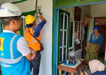 Senyum Patemi, tukang pijat penerima program Light Up The Dream dari PLN UP3 Malang merekah saat petugas memasang jaringan listrik di rumahnya. (Foto/dok.)