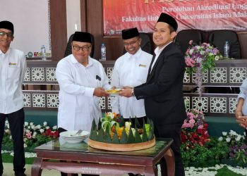Dekan FH Unisma Arfan Kaimudin memberikan potongan tumpeng tasyakuran kepada Rektor Unisma Prof Junaidi. Foto: Azmy