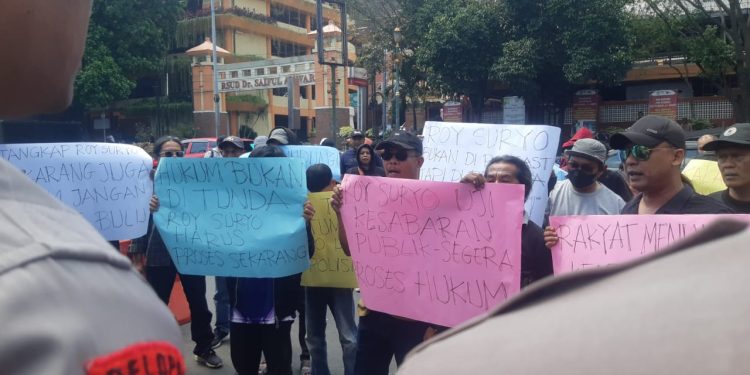 Puluhan massa menggelar aksi di depan Polresta Malang Kota. Mereka melaporkan Roy Suryo. (Foto/M Sholeh)