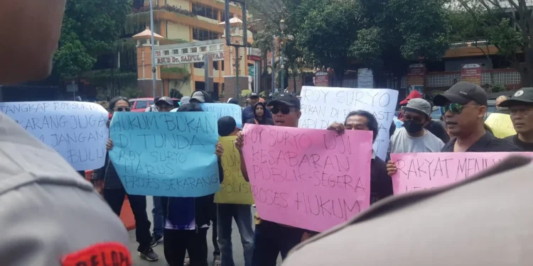 Puluhan massa menggelar aksi di depan Polresta Malang Kota. Mereka melaporkan Roy Suryo. (Foto/M Sholeh)