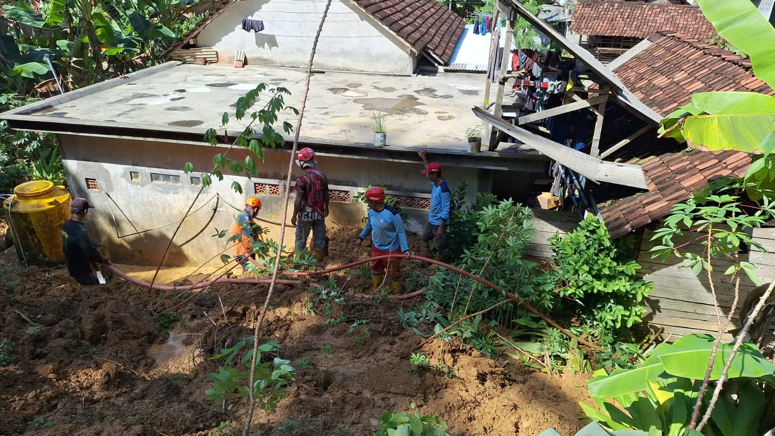 Petugas dan warga bergotong royong membersihkan rumah yang terdampak longsor. Foto: BPBD Kabupaten Malang