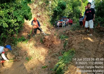 Petugas membersihkan jalan desa yang tertimbun tanahlongsor. Foto: BPBD Kabupaten Malang