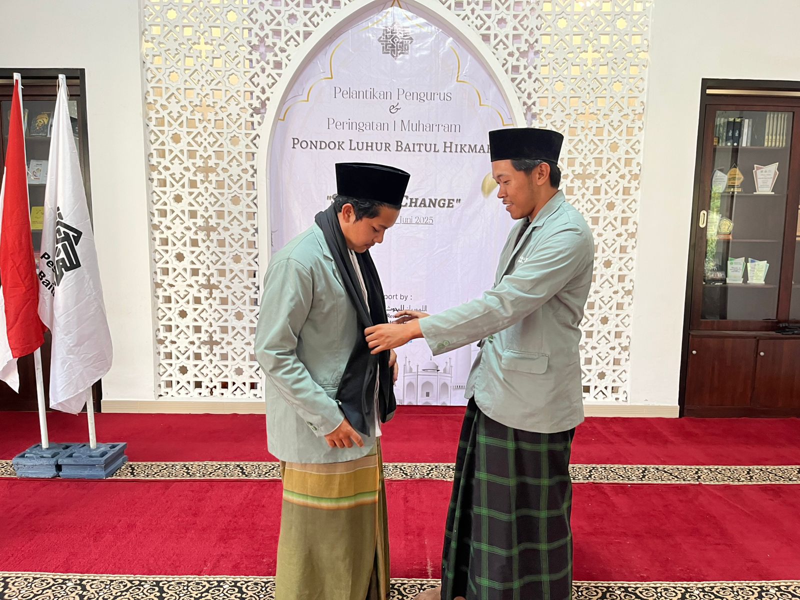 Lurah demisioner, Difan (kanan), secara simbolik menyerahkan estafet kepengurusan pesantren Luhur Baitul Hikmah pada lurah yang baru, Farid (kiri).