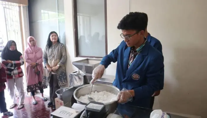 Demonstrasi penggunaan alat pemeras santan kelapa dalam proses pembuatan VCO yang diperagakan mahasiswa Polinema dan mendapat antusiasme dari peserta kegiatan pemberdayaan masyarakat./Foto: Dok.Polinema