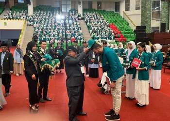 Rektor Unisma, Prof. Drs. H. Junaidi, M.Pd, Ph.D menyematkan topi dan juga jas almamater kepada perwakilan mahasiswa baru Unisma tahun akademik 2025/2026. /Foto: Tugumalang.id/Bagus Rachmad Saputra.