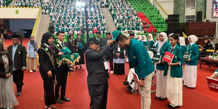 Rektor Unisma, Prof. Drs. H. Junaidi, M.Pd, Ph.D menyematkan topi dan juga jas almamater kepada perwakilan mahasiswa baru Unisma tahun akademik 2025/2026. /Foto: Tugumalang.id/Bagus Rachmad Saputra.