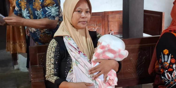 Suliantini menggendong bayinya, Queensa yang menderita hidrosefalus. Foto: Aisyah Nawangsari Putri