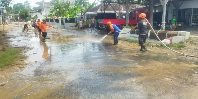Petugas membersihkan dampak banjir di jalanan Desa Sitiarjo. Foto: BPBD Kabupaten Malang