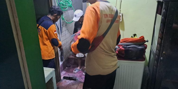 Petugas BPBD Kota Batu saat mengecek lantai rumah warga yang ambles mendadak. Foto: BPBD Kota Batu