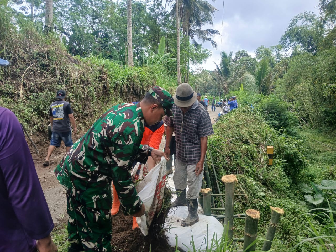Petugas dan warga bekerja bakti membuat penahan jalan sementara. Foto: BPBD Kabupaten Malang