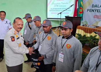 Kepala Bidang Ketentraman dan Ketertiban Umum Satpol PP Provinsi Jawa Timur, Muhammad Tabrani serahkan seminar kit kepada peserta. Foto: Aisyah Nawangsari Putri