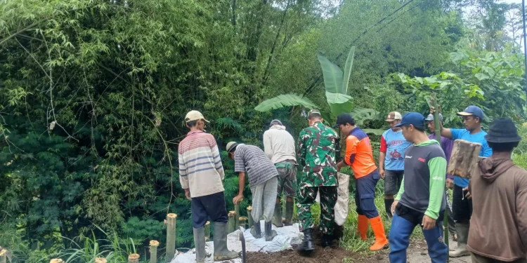 Plengsengan ambrol, petugas dan warga bekerja bakti membuat penahan jalan sementara. Foto: BPBD Kabupaten Malang
