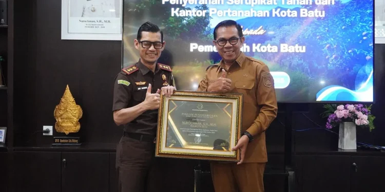 Kajari Batu Andy Sasongko saat menerima penghargaan dari Wali Kota Batu usai berhasil selamatkan aset Pemkot senilai Rp34 miliar lebih. Foto: Azmy
