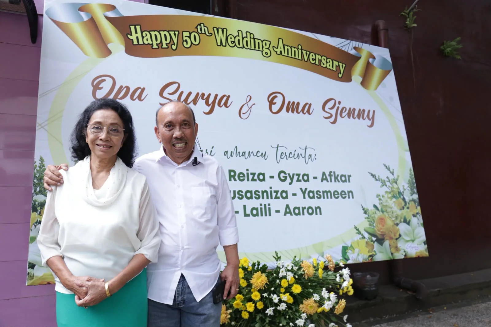 Surya dan Sjenny di sela acara, di depan karangan bunga yang dikirim oleh anak-anak dan cucu mereka. Foto: Rubianto (tugumalang.id)